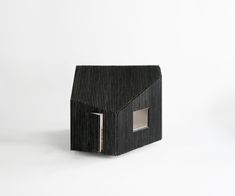 a small house made out of strips of black material with a door open to the outside