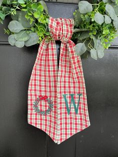 a red and white checkered bow with the letter w hanging from it's front door