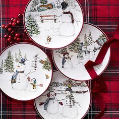 three plates with snowmen painted on them sitting next to a red ribbon and christmas decorations