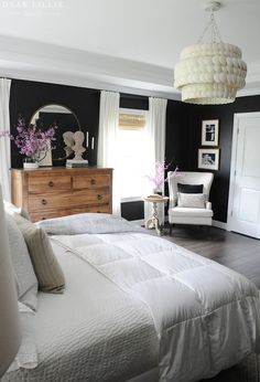 a bedroom with black walls and white bedding