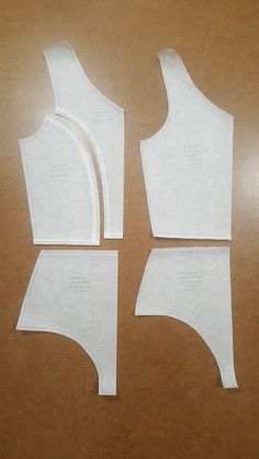 three pieces of paper cut out to look like bras on a wooden table top