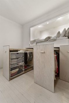 a bed sitting in the middle of a room next to a cabinet with drawers on it