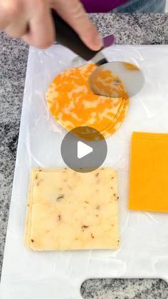 someone is cutting cheese with a knife on top of a plastic bag and another piece of cheese in the background