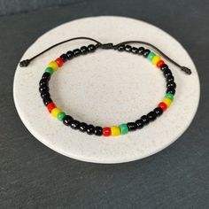 Rastafarian Seed Beads Bracelet, Adjustable Jamaican Bob Marley Style, Reggae Red, Yellow, Green, Black | Unisex Gift | Rastafari Vibes, One Love, Handmade Gift for Her and Him Rasta Bracelet - Radiate the Reggae Spirit! Handmade with a celebration of Rastafari Seed Beads in Jamaican Bob Marley Style. Capturing the Red, Yellow, Green, and Black essence of Reggae, this unisex bracelet is a unique gift for all. Handcrafted Details: Authentic Rastafarian Design: Representing unity, love and positiv Bob Marley Bracelet, Adjustable Black Bohemian Beaded Bracelets, Black 8mm Beads Beach Jewelry, Black Beach Jewelry With 8mm Beads, Black Beaded Jewelry For Beach, 8mm Beads, Traditional Black Adjustable Bracelets, Traditional Adjustable Black Bracelets, Traditional Black Adjustable Beaded Bracelets, Traditional Black Adjustable Bracelet