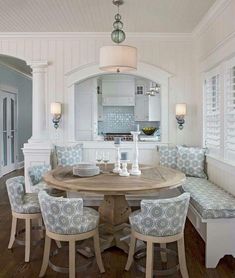 a dining room table with four chairs and a bench in front of an archway that leads to the kitchen