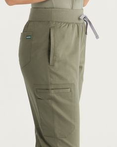 Experience the perfect fusion of fashion and function with our Tanna Cargo Pants, designed to meet the unique needs of the modern healthcare professional. Crafted with meticulous attention to detail, these cargo pants feature a tapered leg style and slim fit, offering a contemporary and flattering silhouette that enhances your workday wardrobe. - Slim fit - Inseam 29 1/2" - Total of seven pockets ✓ Two front pockets ✓ One side pocket with a signature tape on the left side ✓ One side pocket with Straight Leg Joggers With Pockets For Workwear, Functional Workwear Bottoms With Cargo Pockets, Functional Cargo Pocket Workwear Bottoms, Functional Cargo Work Pants, Fitted Utility Cargo Pants With Elastic Waistband, Functional Straight Leg Fitted Cargo Pants, Tapered Leg Workwear Joggers With Pockets, Functional Workwear Pants With Elastic Waistband, Stretch Functional Cargo Pants For Workwear