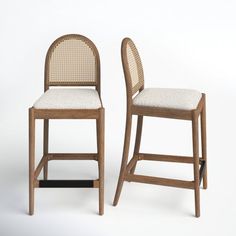 two wooden chairs sitting next to each other on a white surface with no one in it