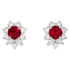 Illuminate your style with the captivating brilliance of Tiffany & Co.'s bright red ruby earrings. Set in platinum, these exquisite gems are embraced by a sparkling diamond halo, evoking a timeless elegance that exudes sheer sophistication. The two red rubies are round shape, and weigh approximately 1.20 total carats. There are 4 marquise and 14 round diamonds that surround the rubies; they weigh approximately 1.00 total carat and are E-F color with VS clarity. They are stamped "© Tiffany & Co.