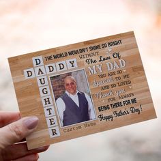 a person holding up a wooden photo frame with the words daddy and dad on it