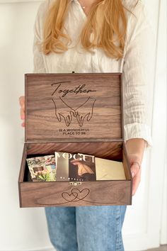 a woman holding an open wooden box with photos in it's front and back