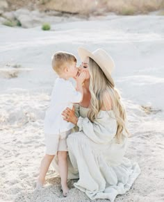 a mother and her son playing in the sand at the beach during their family photo session