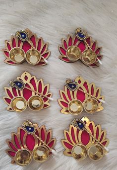 four red and gold brooches sitting on top of a white furnishing