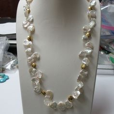 24 karat yellow gold toggle clasp and accented gold beads adorn this keshi pearl necklace. The necklace is 22 inches long including the clasp ends. The pearls are keshi pearls there are not cultured. The color and luster of the pearls are outstanding. The pearls are white, bright luster and white with rose overtone. The pearls measure 14 mm - 15 mm across. There are 8 round 24 karat flat circular beads in the necklace and are high polished. The gold beads measures 10 mm across. I strung the neck Gold Single Strand Baroque Pearl Jewelry, Gold Jewelry With Round Baroque Pearls, Gold Baroque Pearl Bead Jewelry, Gold Baroque Pearl Beaded Jewelry, Yellow Gold Baroque Pearl Single Strand Necklace, Gold Beaded Necklace With Baroque Pearl Chain, Gold Beaded Necklace With Pearl Chain For Anniversary, Gold Beaded Pearl Chain Necklace For Anniversary, Gold Beaded Necklace With Baroque Pearl Pendant