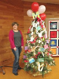 a woman standing next to a decorated christmas tree