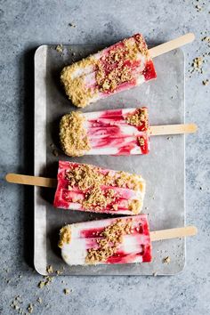 three popsicles with ice cream and crumbled toppings sitting on a tray