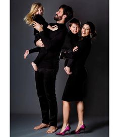 a group of people standing next to each other in front of a gray background with one woman holding the man