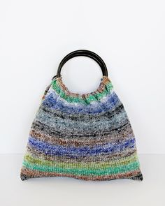 a multicolored knitted bag with a black handle on the front and side