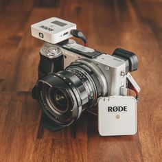 a camera sitting on top of a wooden floor next to a small white box with the word rode written on it