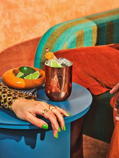 a woman's hand resting on a blue table with a cocktail in the middle