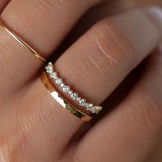 a woman's hand wearing a gold ring with three diamonds on it and the band is