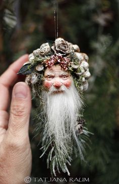 a hand holding an ornament with a white beard