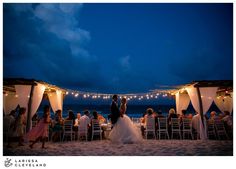 a bride and groom standing under an awning at their wedding reception on the beach