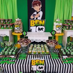 a table topped with lots of cupcakes and desserts next to green curtains