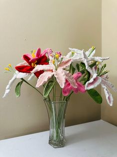 a glass vase filled with flowers on top of a white table next to a wall