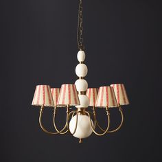 a chandelier with four lamps hanging from it's sides and two shades of red