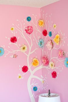 a white tree with colorful flowers on it against a pink wall