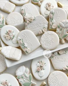 cookies decorated with flowers and names are on a platter, surrounded by other cookies