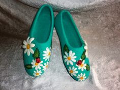 pair of green slippers with ladybugs and daisies on them sitting on a white sheet