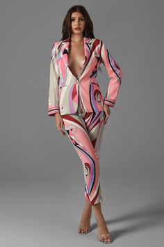 a woman in a pink and white patterned jumpsuit with her hands on her hips