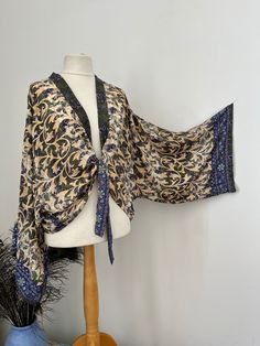 A lovely wide sleeve kimono jacket that was made in India. The fabric used is a soft lightweight silk like fabric called rayon. The patterns a floral and paisley print with gold highlights. The kimono ties up at the front.  It measures around the chest 120 cms  The length is 65 cms. It comes in a lovely fabric bag. Elegant Fall Kimono With Floral Print, Elegant Silk Kimono For Festivals, Elegant Wrap Kimono With Floral Print, One Size Patterned Kimono, Patterned Boho Print Kimono With Kimono Sleeves, Fall Silk Kimono With Open Front, Fall Silk Open Front Kimono, Spring Kimono With Paisley Print And Kimono Sleeves, Elegant Fall Floral Print Kimono