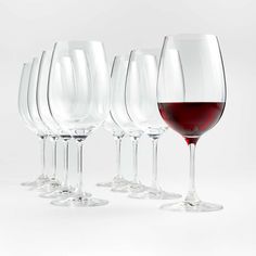 several wine glasses are lined up next to each other on a white surface, with one glass half full and the other half empty