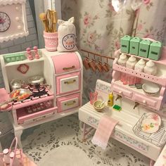 a doll house kitchen with pink and green accessories on the counter, including an oven