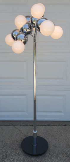 a lamp that is sitting on top of a metal pole in front of a garage door