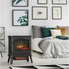 a bed room with a fire in the fireplace and pictures on the wall above it