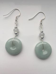 Special sage green jade dangle & drop earrings handmade with quality Chinese jade and 925 Sterling silver hooks and parts. The fine light smoky green jade and white small jade ball are icy and natural. Minimalist and delicate design inspired by traditional Chinese decorations. Some highlights of this pair of cute Chinese jade earrings are: ＊High-quality materials Hand made with grade-A natural green & white jade and 925 sterling silver. ＊Simple and graceful Unique sage green jade donut a Nickel-free Round Jade Jewelry, Nickel-free Round Jade Earrings, Round Jade Jewelry With Matching Earrings, Pierced Jade Dangle Earrings, Natural Stone Jade Dangle Earrings, Dangle Jade Earrings With Matching Set, Jade Dangle Earrings Jewelry Set, Jade Dangle Earrings With Matching Set, Luxury Dangle Jade Earrings With Matching Set