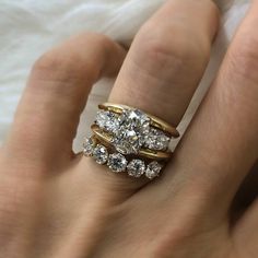 a woman's hand with three rings on top of her finger and two diamonds in the middle