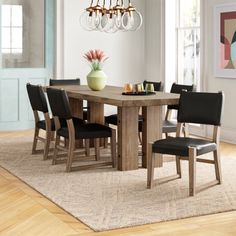 a dining room table with black chairs and a chandelier