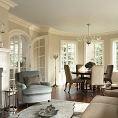 a living room filled with furniture and a fire place under a chandelier in front of a fireplace