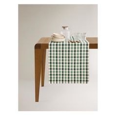 a green and white checkered table runner on top of a wooden table with dishes