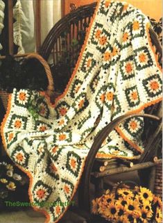 a crocheted blanket sitting on top of a chair next to sunflowers