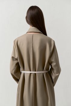 This trench coat features a detachable hem for adjustable length. it has a concealed button closure side slits and seam pockets. a decorative cut-out beneath the back collar and raw seams along the center front and back. made from merino wool produced at a factory in the piedmont region of italy. made in our studio in chișinău moldova.    composition – wool 100%; viscose lining 100%  model is 175 / 5'9" and wears a size s Elegant Single Breasted Khaki Outerwear, Elegant Single-breasted Khaki Outerwear, Elegant Khaki Outerwear With Lapel Collar, Khaki Long Coat With Hidden Button Closure, Tailored Khaki Outerwear For Office, Chic Khaki Gabardine Outerwear, Chic Khaki Outerwear With Belted Cuffs, Khaki Outerwear With Hidden Button For Work, Elegant Khaki Outerwear With Belted Cuffs