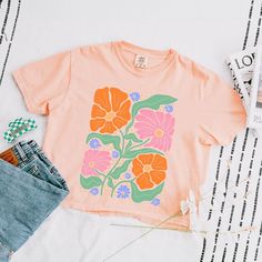 Looking for a cute versatile top to wear? Make sure to grab one of our Graphic Tees! This soft and comfortable graphic Tee is the perfect top for any outfit. It can be paired with biker shorts, jeans, or even a simple skirt/dress! This Tee is true-to-size, so be sure to order your regular t-shirt size! If you are looking for a more oversized look, make sure to size up! Spring Cotton Crop Top T-shirt, Casual Peach T-shirt With Graphic Print, Trendy Orange Short Sleeve Crop Top, Relaxed Fit Pink Top With Funny Print, Orange Crew Neck Top With Graphic Print, Pink Graphic Print Cotton Crop Top, Spring Peach Graphic Print T-shirt, Spring Peach T-shirt With Graphic Print, Pink Cotton Crop Top With Graphic Print