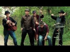 the men are playing music together in the woods and posing for a photo with their instruments