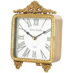 a clock that is gold and white with roman numerals on the face, sitting in front of a white background