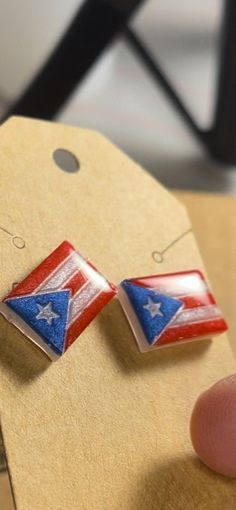 a pair of red, white and blue earrings is being held by someone's finger