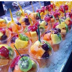 many different kinds of fruit in plastic cups